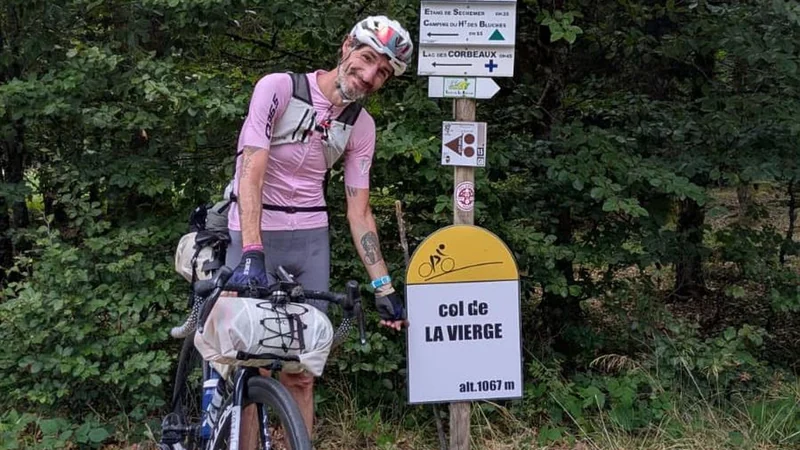 Un ciclista junto a su bicicleta en un puerto de montaña.