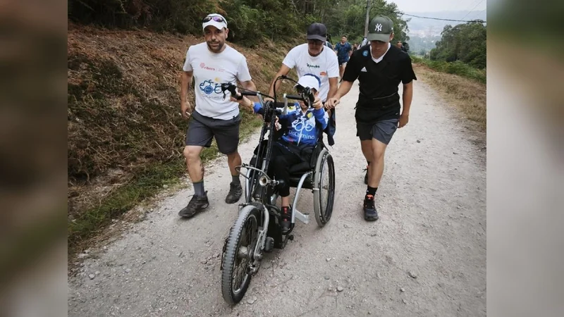 Un grupo de personas acompaña a un niño en una silla adaptada por un camino.